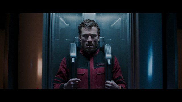 A close-up shot of a man wearing a white suit and a white hat, looking intently at someone in a retail store filled with merchandise.