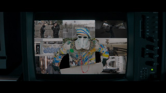 A shocked man with long hair and a baseball cap sitting in a bar, looking surprised.