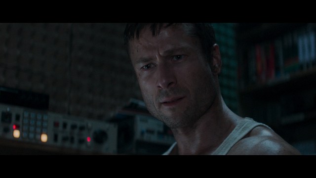 Aerial view of futuristic skyscrapers with cars driving vertically up the side of a building, showcasing a modern urban landscape.