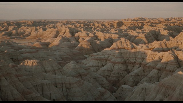 A close-up shot of a man with a distressed expression, featuring dark hair and wearing a blue hoodie, against a softly lit background.