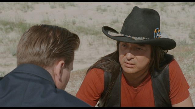 A worried woman stands on a deserted road, looking shocked or distressed as she gazes into the distance.