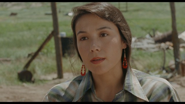 Two men are engaged in conversation at a colorful playground with bright slides in the background.