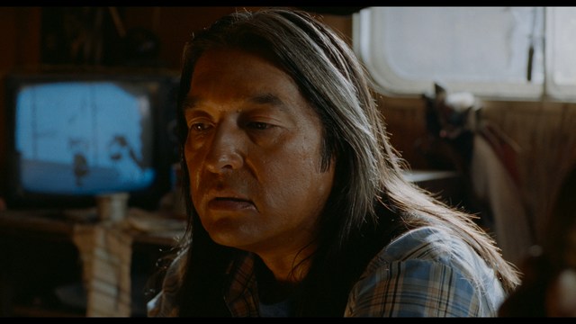 Two characters wearing red bandanas look surprised while standing in a dimly lit indoor setting.