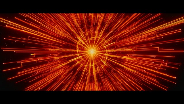 A serious-looking cardinal stands in front of a wooden backdrop with colorful posters related to Catholicism, holding a microphone at a press conference.