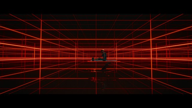 Statue of a smiling figure resembling Jesus, giving a thumbs up gesture, set against a colorful backdrop with signs related to Catholicism.