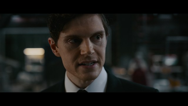 A close-up shot of a man with a distressed expression, featuring dark hair and wearing a blue hoodie, against a softly lit background.