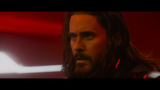 Two characters sitting in a diner, one wearing a blue beanie with 'SNOOGANS' and the other wearing a cap, both looking intently at something off-screen.