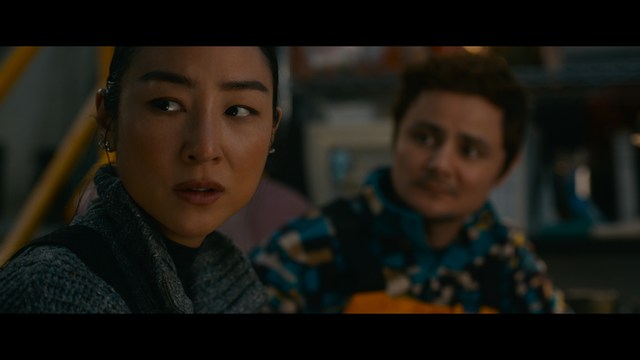 A woman with dark hair and a neutral expression sitting in a retro diner setting.