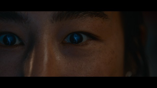 A young man pointing a handgun while seated in a bus, showcasing an intense expression.