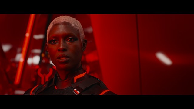 A scene featuring a man with short hair and a beard, wearing a brown jacket and purple shirt, standing outside a restaurant with bright yellow walls and a cartoon cow logo.