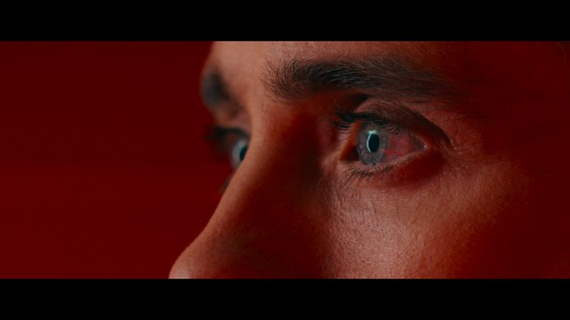 Two men are engaged in conversation at a colorful playground with bright slides in the background.