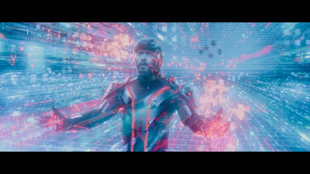 A man with short hair and a beard sits at a table, looking surprised or excited while holding a bottle.