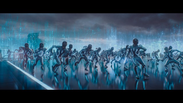 Two young men are looking at something off-camera, standing inside a building with bright lighting and seating areas visible in the background.