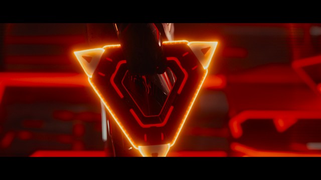 A tense scene featuring a woman with long hair and a serious expression, looking off to the side, while a man with short hair sits in the background, appearing relaxed and slightly turned away.