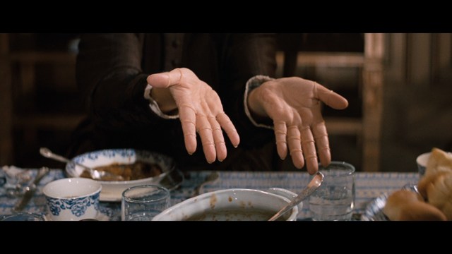 Three teenagers sitting on the floor, each holding a hockey stick, with two laughing and one looking serious. The background features a room with neutral-colored walls.