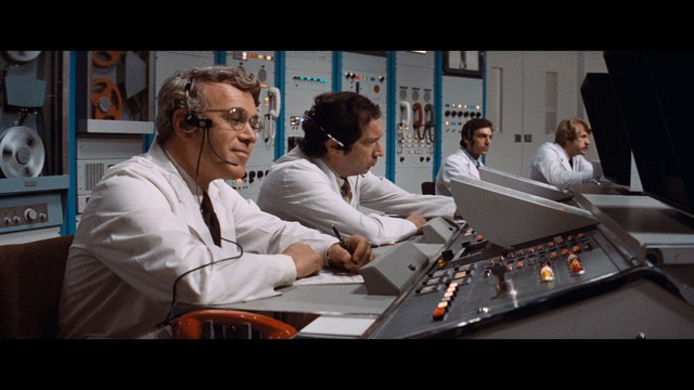 A woman with a shocked expression standing in the middle of a deserted road surrounded by lush greenery.