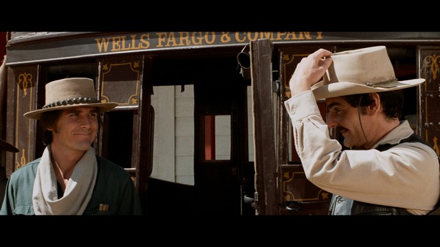 A close-up of a person's hand holding a crumpled newspaper with the headline "Mooby's: Creating an Empire Out of Simplicity" and a graphical chart showcasing growth, titled "It was a very Good YEAR."