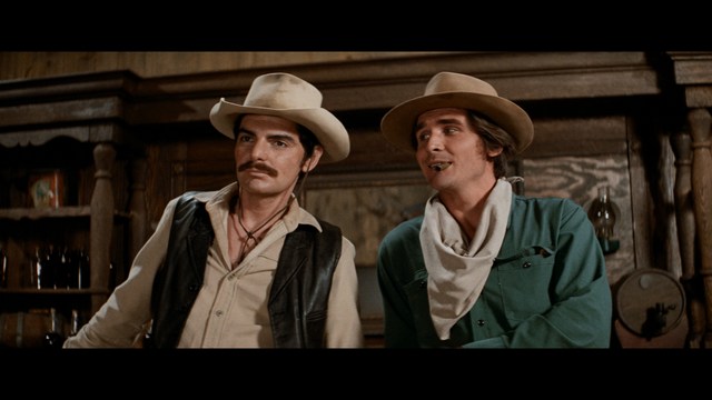 Four anthropomorphic turtles in ninja attire stand in a dimly lit room, while a humanoid character with fur sits nearby.