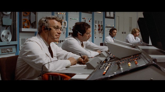 A worried woman stands on a deserted road, looking shocked or distressed as she gazes into the distance.