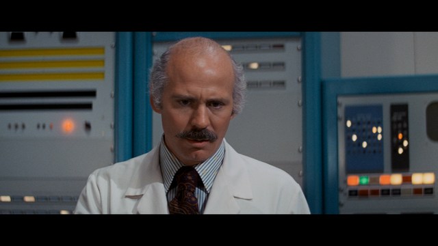 A scene featuring five characters in a bar setting, with a focus on their expressions and interactions. The backdrop includes bar shelves with bottles and a bartender visible in the background.