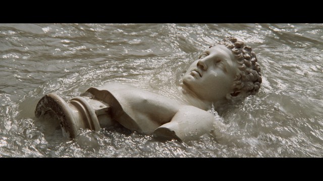 Two figures walking on a road towards a blue 'Welcome to New Jersey' sign.