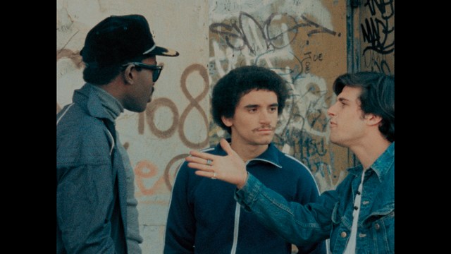 A close-up shot of a man with a distressed expression, featuring dark hair and wearing a blue hoodie, against a softly lit background.
