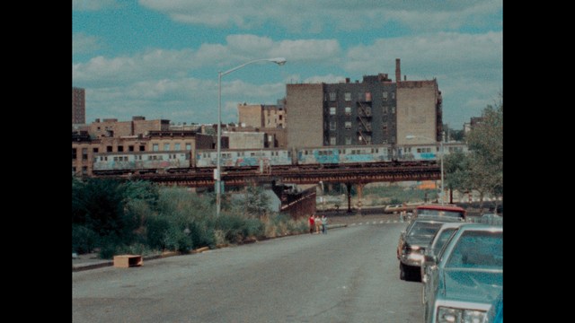 A close-up shot of a man wearing a white suit and a white hat, looking intently at someone in a retail store filled with merchandise.